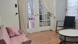 Ein Zimmer mit einem rosa Sofa, einem runden Tisch und einem Stuhl.