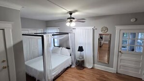 Ein Schlafzimmer mit einem Himmelbett, einem Deckenventilator und einer Tür mit Spiegel.