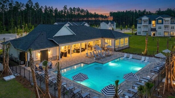Un hotel con piscina, mobiliario exterior y un patio bien iluminado.