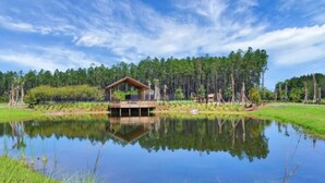Una cabaña junto al lago con un balcón, rodeada de un bosque y un lago tranquilo.