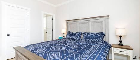 Un dormitorio con cama, mesitas de noche, una puerta y un ventilador de techo.