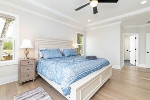 Ein Schlafzimmer mit Bett, Nachttischen, Deckenventilator und Fenster.