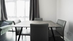 A modern room with a large table, four chairs, a sofa, and a window with curtains. - Spacious Flat Near to Barnet Hospital (Barnet)