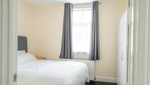 A hotel room with two beds, a window with curtains, a radiator, and a wardrobe. - Spacious Flat Near to Barnet Hospital (Barnet)
