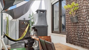 Un patio con hamaca, mobiliario exterior, una parrilla y una planta en maceta.