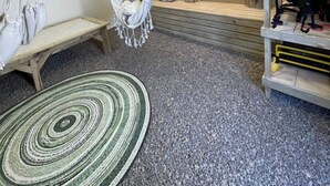 Una habitación con una silla colgante de macramé, un banco de meditación, una esterilla de yoga, un estante con equipo de yoga y una estatua.