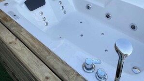 Una bañera de hidromasaje con estructura de madera, panel de control y llave.