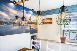 Une cuisine moderne avec des luminaires suspendus, une fresque murale, une plante en pot et une fenêtre offrant une vue agréable.