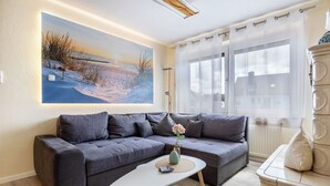 Una sala de estar moderna con un sofá modular, una mesa de centro, un cuadro y un ventanal con cortinas.