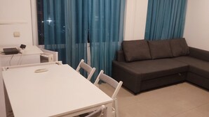 Un soggiorno moderno con un tavolo bianco, un divano grigio e tende blu.