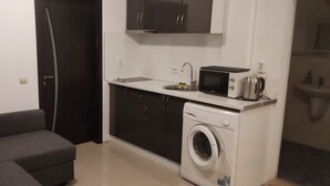 Una cucina compatta con lavatrice, forno a microonde e lavello.