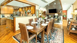 A modern kitchen with wooden cabinets, a central island, and a dining area with a wooden table and chairs.