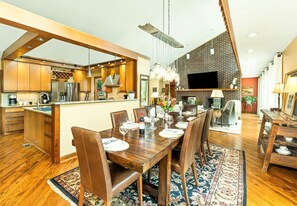 Une cuisine moderne avec des meubles en bois, un îlot central et un coin repas comprenant une table et des chaises en bois.