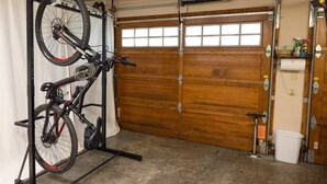 A garage with a bicycle rack, a wooden garage door, and a white bucket.