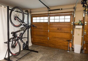 Un garage équipé d’un porte-vélo, d’une porte de garage en bois et d’un seau blanc.