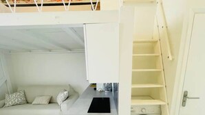 Un espace de vie compact comprenant une kitchenette, un lave-linge et un canapé.