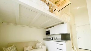 Un intérieur moderne comprenant un canapé, un coin cuisine et un escalier menant à un niveau supérieur.