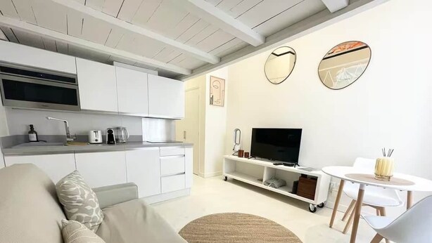 Un salon moderne comprenant un canapé, un téléviseur, une table à manger et un coin cuisine.
