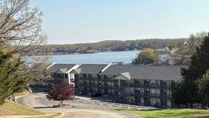 A multi-story building with a parking lot in front, overlooking a body of water. - Lake front 1-bedroom condo in charming Osage Beach convenient location (Osage Beach)