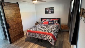 A bedroom with a bed, a ceiling fan, a wooden door, and a framed picture on the wall. - Lake front 1-bedroom condo in charming Osage Beach convenient location (Osage Beach)