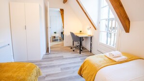 Een slaapkamer met twee bedden, een bureau en een stoel.