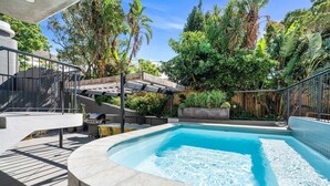 Une piscine à bordures courbes, entourée d’une terrasse en béton et de rampes métalliques.