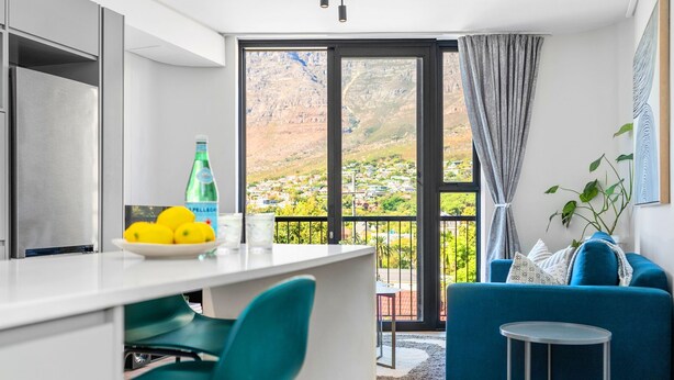 Une cuisine moderne avec un coin repas, un canapé bleu et une vue sur un paysage montagneux.