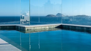 A clear blue sky, a swimming pool with a glass enclosure, and distant buildings. - Ipanema Penthouse w/ Pool by the Beach (Rio de Janeiro)