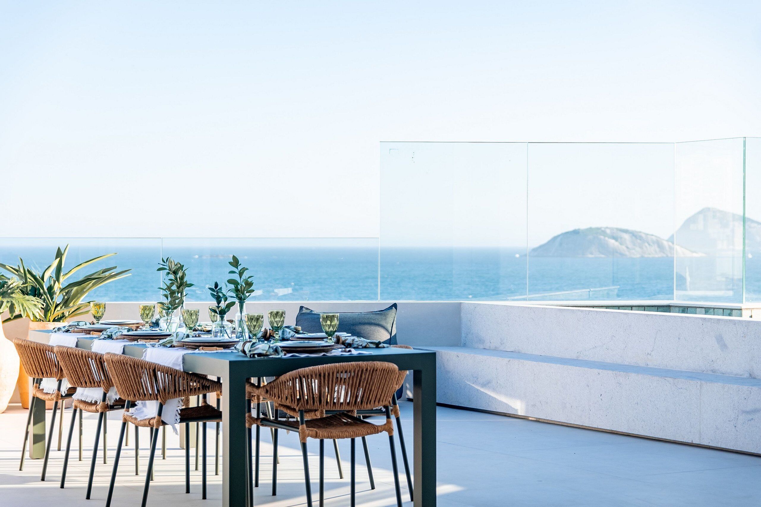 A dining area with a table set for four, overlooking the sea.