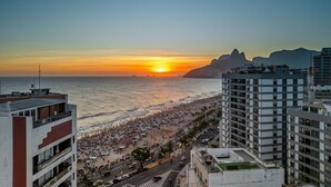 A coastal cityscape with a beach, buildings, and a sunset. - Ipanema Penthouse w/ Pool by the Beach (Rio de Janeiro)