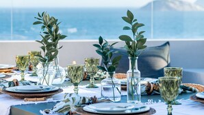 A dining table set with glassware and greenery, overlooking a coastal view. - Ipanema Penthouse w/ Pool by the Beach (Rio de Janeiro)