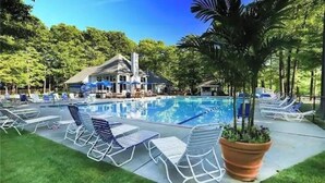 Piscina com espreguiçadeiras e um edifício ao fundo.