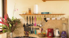 Eine Küche mit verschiedenen Küchengeräten, die an der Wand hängen, einem Herd, einer Kaffeemaschine, einem Wasserkocher und einem Mixer.