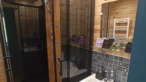 Et træinteriør med et glasafskærmet brusebad, en vask og et spejl.