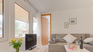Una sala de estar moderna con un sofá, un televisor, una mesa de centro y un florero con flores.