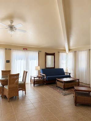 A hotel room with a blue sofa, wicker furniture, a ceiling fan, and a tiled floor. - Tranquil North Ambergris Caye Retreat - 3BR Home - Sleeps 8 (San Pedro)