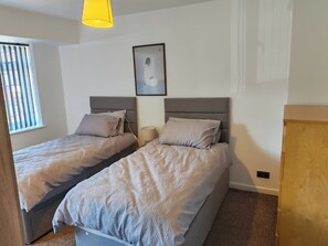 A bedroom with two beds, a window with blinds, a lamp, and a framed picture on the wall. - Coventry House Near City Centre & A45 (Coventry)