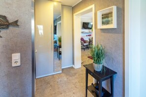A hallway with a potted plant, a framed picture, and a fish decoration on the wall. - Vacation apartment Meeresrauschen (Hagermarsch)