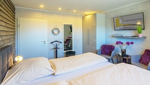 A hotel room with a bed, a mirror, a shelf with flowers, and a wall sign. - Vacation apartment Meeresrauschen (Hagermarsch)