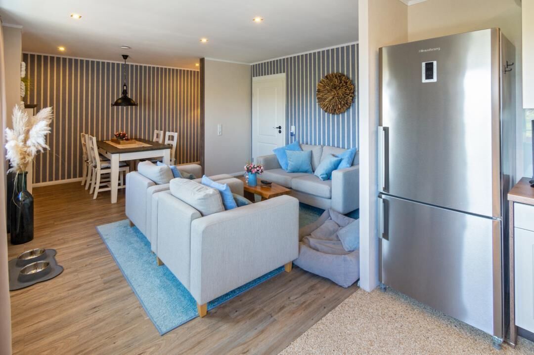 A modern living room with a sofa, a dining table, and a refrigerator.