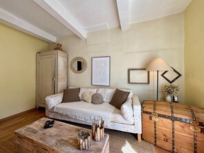 A cozy living room with a sofa, a wooden chest, a lamp, and a framed picture on the wall. - La Nothé, charming house by the harbor & lagoon (Bouzigues)