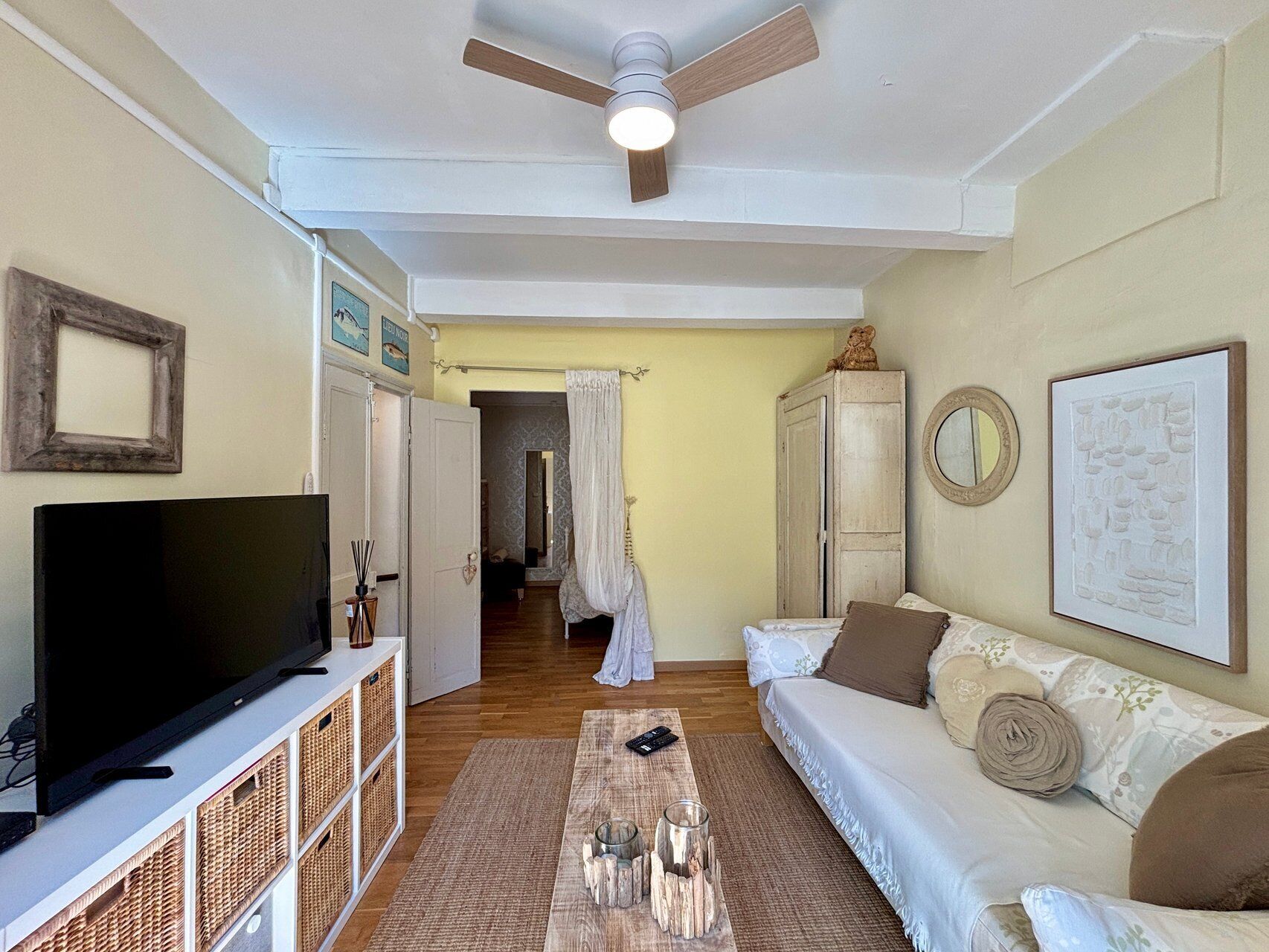 Una sala de estar con televisión, ventilador de techo, sofá y mesa de centro.