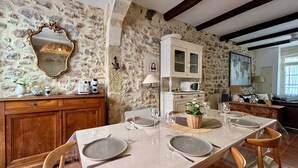 Un coin repas agrémenté d’un mur en pierre, d’un buffet en bois et d’une table blanche dressée pour quatre personnes.