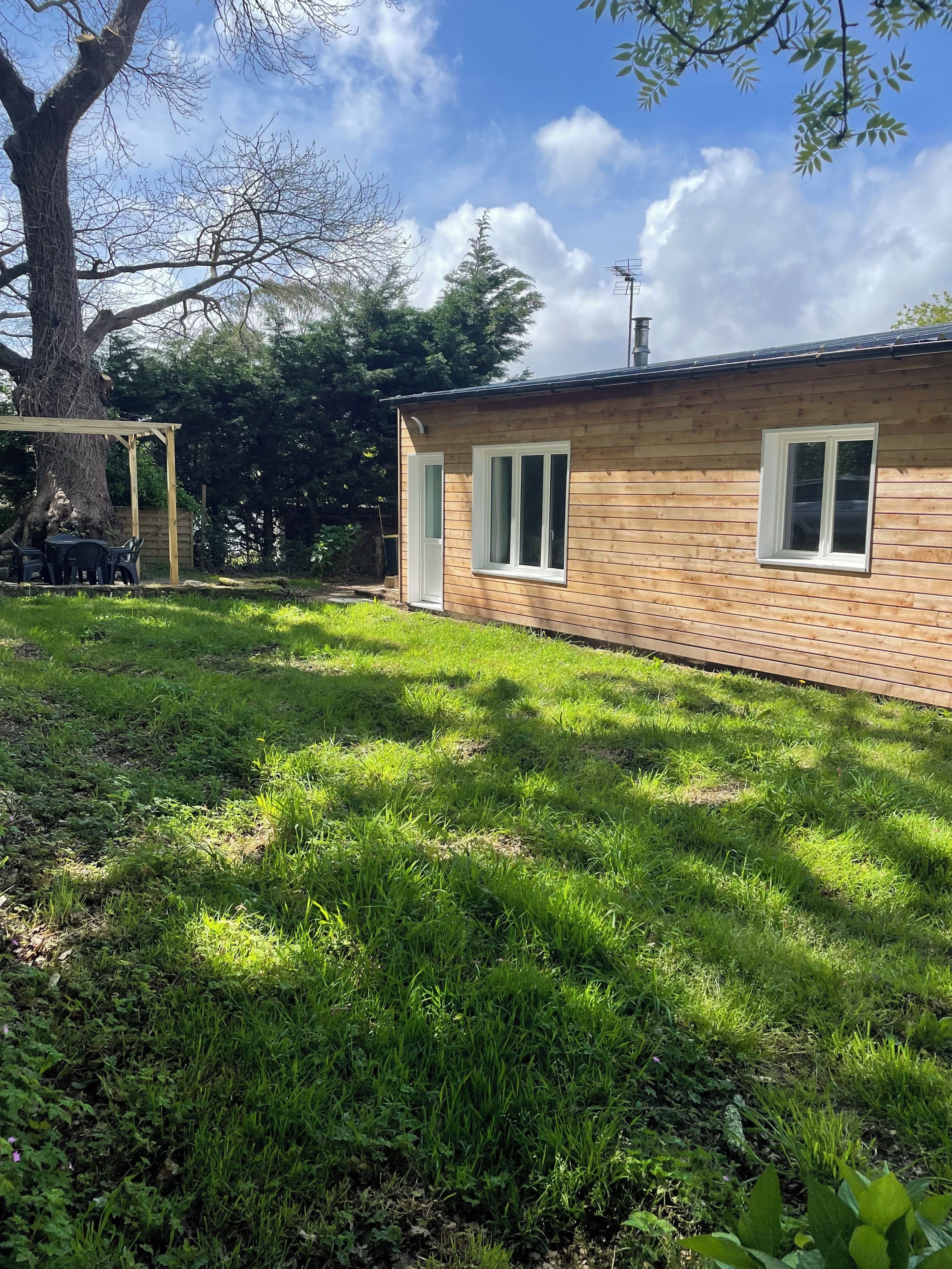A wooden house with a covered patio and a grassy yard.