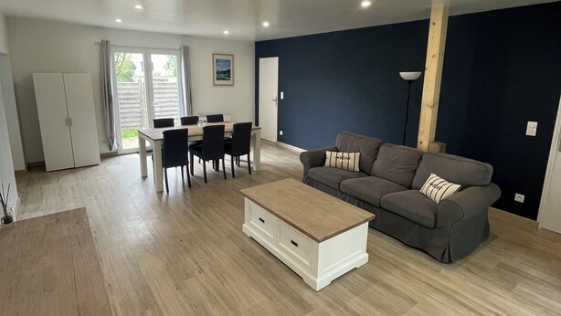 Ein geräumiger Wohnbereich mit Sofa, Couchtisch, Esstisch, Stühlen und einem Kleiderschrank.