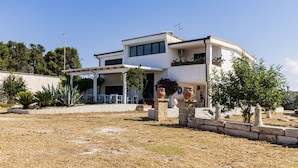 Een modern huis met twee verdiepingen, een plat dak, grote ramen en een overdekte patio.