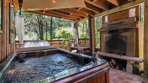 A hot tub, a fireplace, and a wooden deck with a view of trees. - Simply Nature in the City (Smyrna)