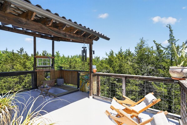 Una terraza de madera con sillas de descanso, una mesita y un mural.