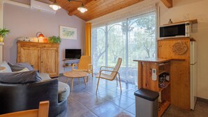 Una sala de estar acogedora con un sofá, sillones, un televisor y una zona de cocina con microondas.