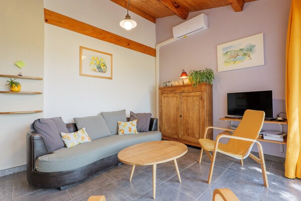 A living room with a sofa, a wooden cabinet, a TV, and a chair.